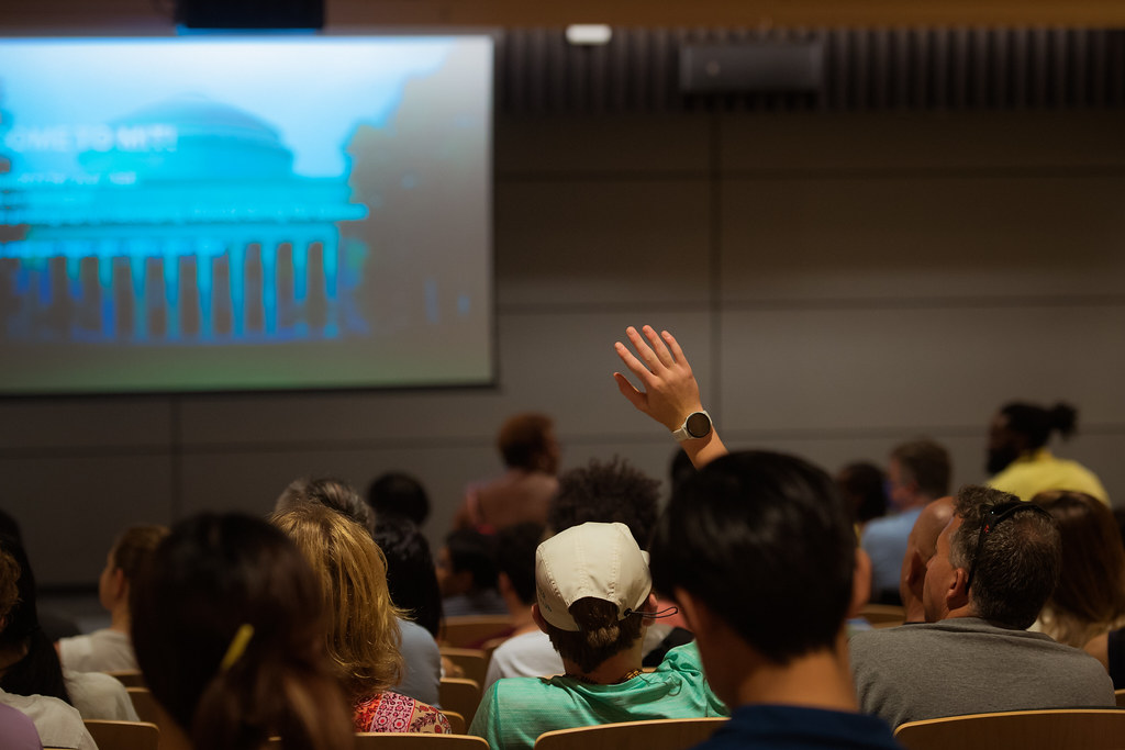 Students in college lecture hall with hand raised